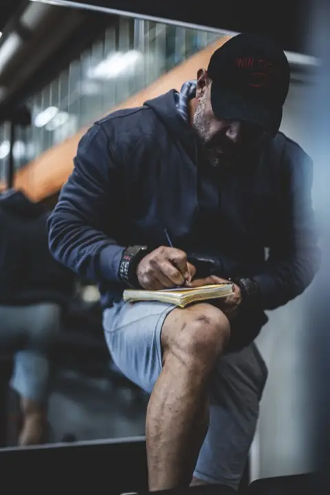 Ashkan Aghili antecknar i en träningsdagbok mellan set på gymmet